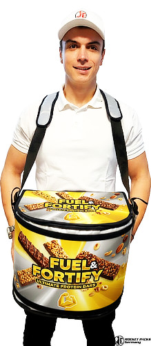 Rocketpacks hawker's tray in a sleek white finish, featuring a luxury metallic gold and silver advertisement across the front. The scene displays a professional vendor in a crowded stadium environment, utilizing the ergonomic padded strap system for maximum comfort during long shifts. The tray is shown with high-quality textures and realistic lighting, emphasizing the durable, professional-grade construction used for mobile beverage and snack sales.