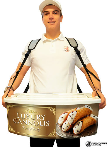 Professional Rocketpacks hawker's tray in a sleek white finish, featuring a luxury gold and silver metallic "Cannoli Siciliani" advertisement. The scene shows a server in a vibrant event setting, presenting fresh cannoli to guests. The tray highlights the premium material craftsmanship and the ergonomic dual-shoulder strap system, designed for high-end mobile dessert service and gourmet product presentation.