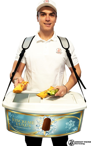 Rocketpacks ice cream vendor tray in a sleek white finish, featuring a luxury gold and black "Frozen Delights" advertisement. The image shows a professional vendor serving a fresh ice cream cone to a customer at a sunlit outdoor festival. The tray displays multiple chilled containers and cones, highlighting the high-quality material and ergonomic design used for professional mobile vending.